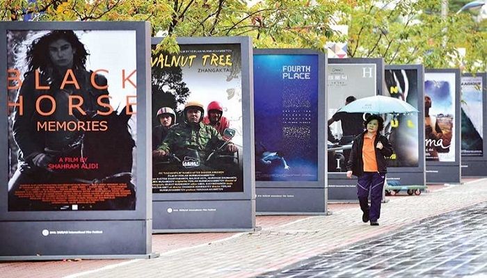 In a file photo taken on October 1, 2015, a woman walks past cinema posters for the Busan International Film Festival (BIFF) at the Busan Cinema Centre in Busan. — AFP photo