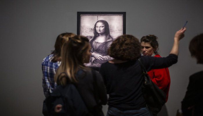 Journalists gather near a Mona Lisa image by Leonardo da Vinci during a visit at the Louvre museum Sunday, Oct. 20, 2019 in Paris. A unique group of artworks is displayed at the Louvre museum in addition to its collection of paintings and drawings by the Italian master. The exhibition opens to the public on Oct.24, 2019. (AP Photo)