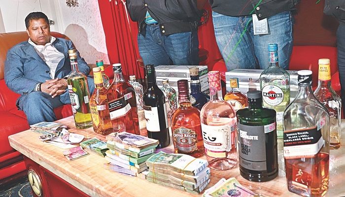Bottles of liquor, bundles of money, and foreign currencies seized from the Gulshan home of Salim Prodhan, seated. Rab detained Salim on Monday from Hazrat Shahjalal International Airport on charges of laundering money. Photo: Collected