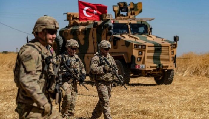 In this AFP file photo taken on September 08, 2019 US troops walk past a Turkish military vehicle during a joint patrol with Turkish troops in the Syrian village of al-Hashisha on the outskirts of Tal Abyad town along the border with Turkish troops.