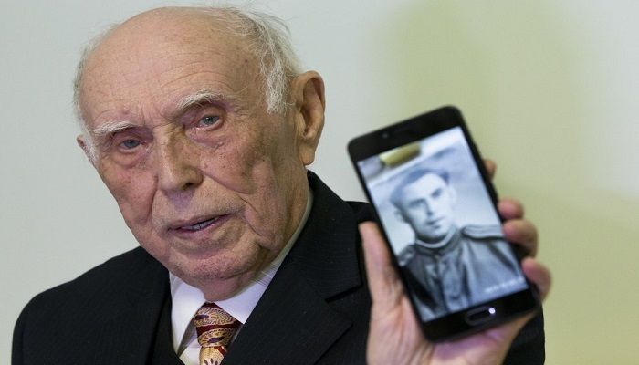 Holocaust survivor WWII veteran Mikhail Spectr, 86, shows a photo of him in Soviet Army officer's uniform to the media at the annual Hanukkah Menorah Lighting Ceremony in Moscow, Russia, Sunday, Dec. 22, 2019. Spectr was taken to Jewry in 1941 at the age of 8 when Nazi soldiers arrived at his village in Ukraine Soviet republic. Mikhail Spectr had been kept at ghetto in Transnistria, territory between Dniester and Southern Bug, occupied by the Nazi and its allies from 1941 and 1944. Photo: AP