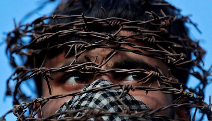 A masked Kashmiri man with his head covered with barbed wire attends a protest after Friday prayers, during restrictions following the scrapping of the special constitutional status for Kashmir by the Indian government, in Srinagar, October 11, 2019. REUTERS