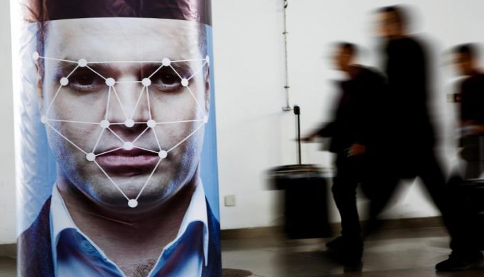 People walk past a poster simulating facial recognition software at the Security China 2018 exhibition on public safety and security in Beijing, China October 24, 2018. Photo:REUTERS 