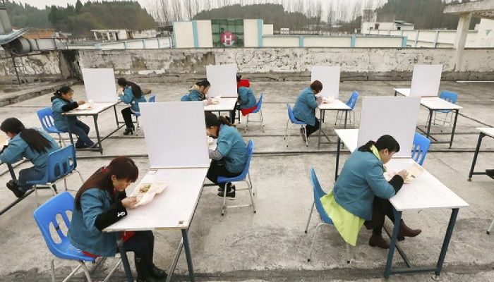 In this Friday, Feb. 14, 2020, photo, factory workers are separated by partitions as a precaution against infection as they take their lunch break on the roof of an electronics factory in Suining in southwestern China's Sichuan Province. China reported Saturday a figure of 2,641 new virus cases, a major drop from the higher numbers in recent days since a broader diagnostic method was implemented. Photo: Collected from Chinatopix via AP