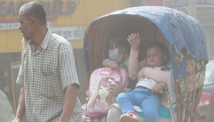 A mother carries her child while her school-going daughter wore a mask because of the smog. Photo: Collected from UNB