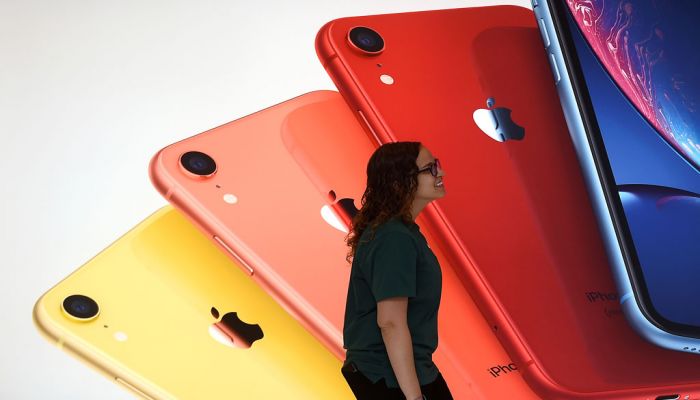 An Apple Store employee walks past an illustration of iPhones at the new Apple Carnegie Library during the grand opening and media preview in Washington, US, on May 9, 2019 Reuters