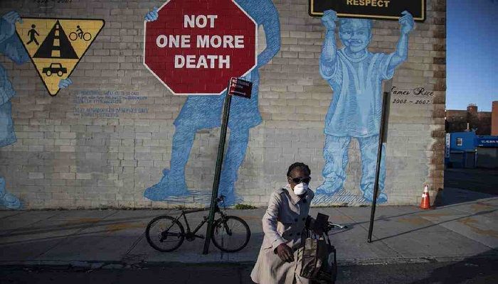 A woman wearing a mask crosses the street in front of a mural about traffic accidents reading, "NOT ONE MORE DEATH" in the Brooklyn borough of New York. Photo: Collected from AP 