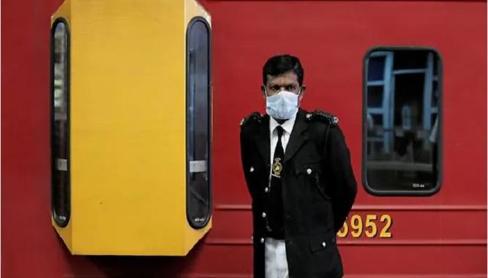 A conductor wears a protective mask as he stands next to a train at Fort railway station in Colombo, Sri Lanka. Photo: Collected from Reuters