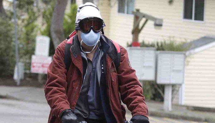 A man wearing a mask and goggles rides his bike out of the parking lot at the Life Care Center is shown in Kirkland. Tuesday, March 3, 2020. Photo: Collected from AP
