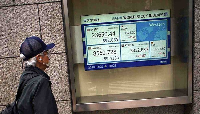 A man wearing a mask against the spread of the new coronavirus looks at an electronic stock board showing world stock indexes at a securities firm in Tokyo Tuesday, April 21, 2020. Photo: Collected