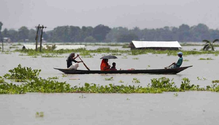A family travels in a country boat over floodwaters in Gagolmari village, in Morigaon district of Assam, India. Photo: Collected from AP 