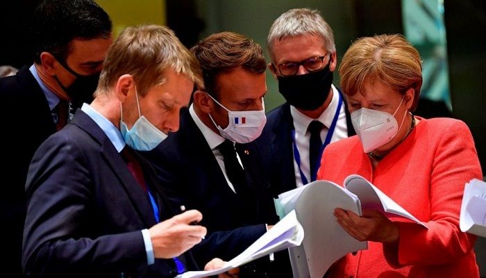 German Chancellor Angela Merkel, right, speaks with French President Emmanuel Macron, center, during a round table meeting at an EU summit in Brussels, Monday, July 20, 2020. Weary European Union leaders are expressing cautious optimism that a deal is in sight on their fourth day of wrangling over an unprecedented budget and coronavirus recovery fund. Photo: AP 