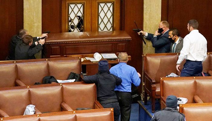 Capitol police officers point guns at a protester from inside the Senate chamber. Photo: Collected from Reuters