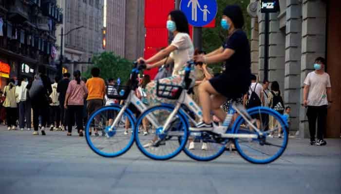 Woman ride bikes on a street, following the outbreak of the coronavirus disease (COVID-19), in Shanghai, China. Photo : Rueters 