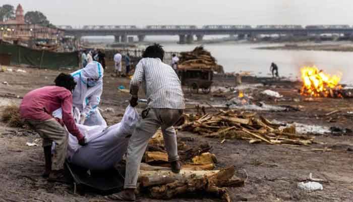 People place the body of a man who died from the coronavirus disease (COVID-19), on a pyre before his cremation on the banks of the river Ganges at Garhmukteshwar in the northern state of Uttar Pradesh, India, May 6, 2021. Photo: Reuters 