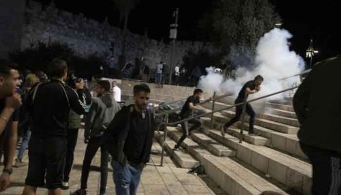Palestinians react to stun grenades fired by Israeli police to clear the Damascus Gate to the Old City of Jerusalem after clashes at the Al-Aqsa Mosque compound, Friday, May 7, 2021. Photo: AP 