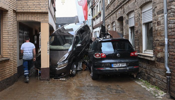A local resident walks past damaged cars in a street in Bad Neuenahr-Ahrweiler, western Germany, on July 16, 2021, after heavy rain hit parts of the country, causing widespread flooding and major damage. || AFP Photo: Collected