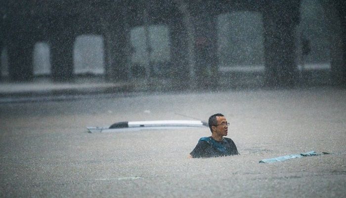 (Zhengzhou, China) A person attempts to wade across the floodwaters caused by torrential rain. (Photograph: Rex/Shutterstock)