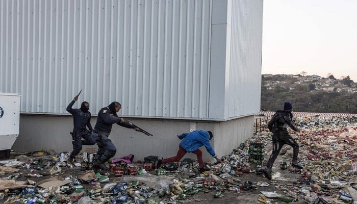 (Durban, South Africa) Two police officers chase and shoot rubber bullets at suspected looters outside a warehouse storing alcohol. (Photograph: Guillem Sartorio/AFP/Getty)