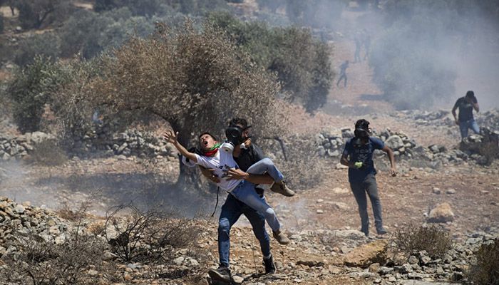 (Beita, West Bank) Palestinians carry a boy as they take cover from the teargas canisters fired by Israeli soldiers during a protest against the West Bank Jewish settlement of Eviatar that was established last month. || Photograph: AP