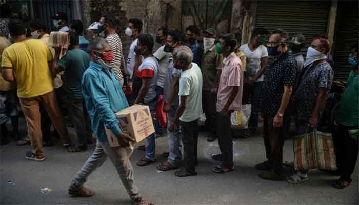 People queue to buy alcohol after West Bengal's government announced a 15-day lockdown amid the Covid-19 pandemic, in Siliguri on May 15, 2021. || Photo: AFP