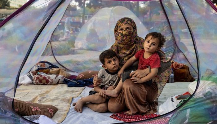 (Kabul, Afghanistan) Farzia, 28, who lost her husband in Baghlan one week ago fighting the Taliban, sits with her children, Subhan, five, and Ismael, two, in a tent at a makeshift camp in Shahr-e Naw park. People displaced by the Taliban advance are flooding into Kabul to escape the takeover of their provinces. (Photograph: Paula Bronstein/Getty Images)
