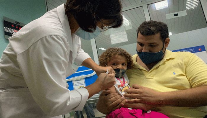Pedro Montano holds his daughter Roxana, 3, as she is inoculated against Covid-19 at the Juan Manuel Marquez hospital, Havana, August 24 2021. || AFP Photo: Collected