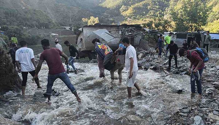 People wade past a flooded area in Dipayal Silgadhi, Nepal, Thursday, Oct. 21, 2021. Floods and landslides triggered by days of torrential rains have killed at least 99 people in Nepal since Monday, officials said. || AP Photo: Collected