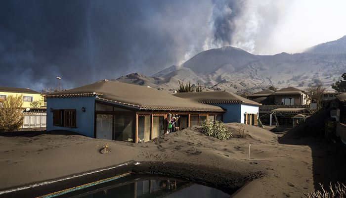 La Palma, Spain || Cristina Vera leaves her house, covered with ash from volcano eruptions, after collecting the last of her belongings. || Photograph: Emilio Morenatti/AP