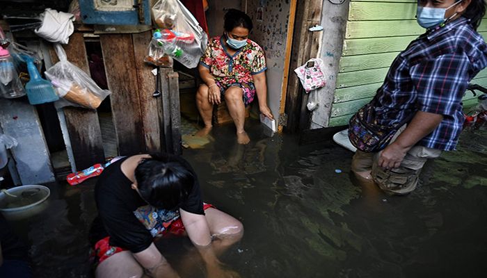 Bangkok, Thailand || Residents sit on the doorsteps of their flooded home as water from the Chao Praya river floods low lying areas around the district of Bang Phlat || 
Photograph: Lillian Suwanrumpha/AFP/Getty Images