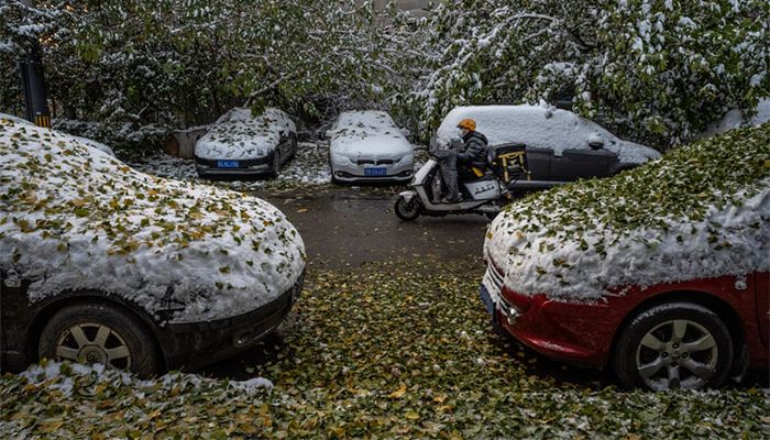 Beijing, China || A delivery driver rides a scooter past cars covered in snow and leaves following a snowfall in Beijing. The city, which averages less than seven days of snow annually, is set to host the 2022 Winter Olympics next February || Photograph: Kevin Frayer/Getty Images