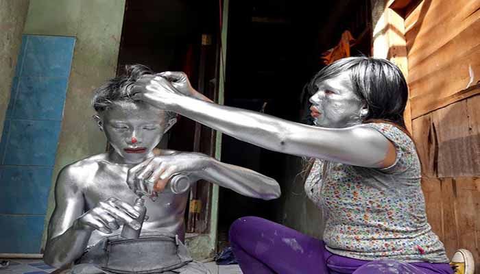 Puryanti, a 29-year-old woman, and her 15-year-old nephew Raffi, cover themselves from head to toe in silver paint to become 'manusia silver' (silver people), as part of their act to make a living, on the outskirts of Jakarta, Indonesia, February 6. || Photo: REUTERS