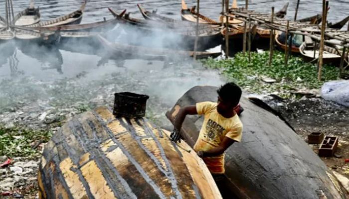 A worker repairs a boat along the banks of the Buriganga River in Dhaka on January 12, 2022 || AFP Photo: Collected  