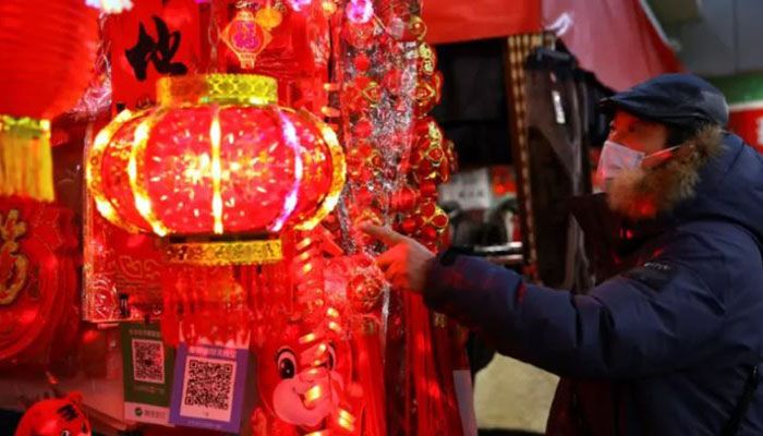 A customer looks at decorations for Chinese Lunar New Year displayed at a stall inside a morning market in Beijing, China January 14, 2022. || Reuters Photo: Collected 