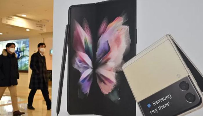 People walk past an advertisement for the Samsung Galaxy Z Fold3 and Flip3 smartphones at the company's Seocho building in Seoul on January 7, 2022 || AFP Photo: Collected  