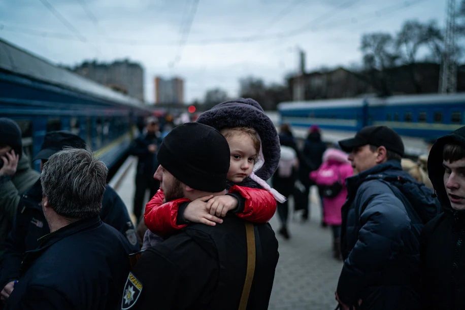 A child is carried on board as Ukrainian women and children, along with some men who came to say goodbye before going back to fight, rush for a train to Lviv from the station in Odessa || Photo: Salwan Georges/The Washington Post