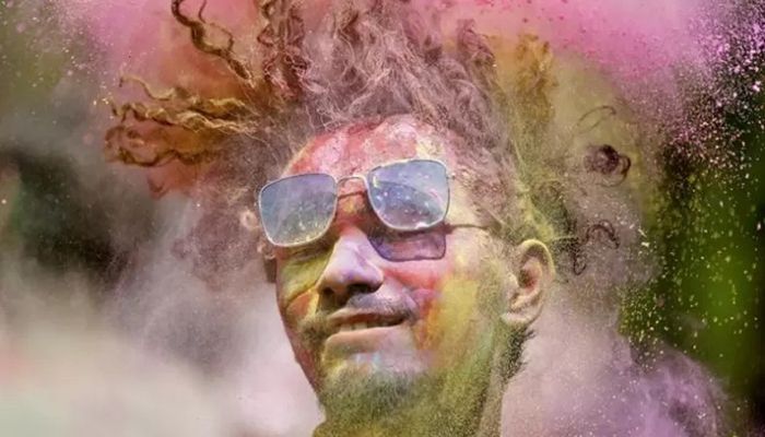 A man covered in colored powder shakes his head during Holi celebrations in Ahmedabad, India, March 17, 2022 || Reuters Photo: Colllected 