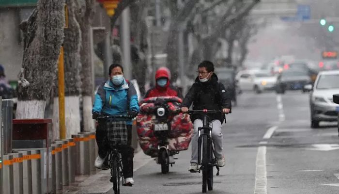 People ride bikes on a street amid snowfall, following the coronavirus disease (Covid-19) outbreak, in Beijing, China March 17, 2022. || Reuters Photo: Collected  
