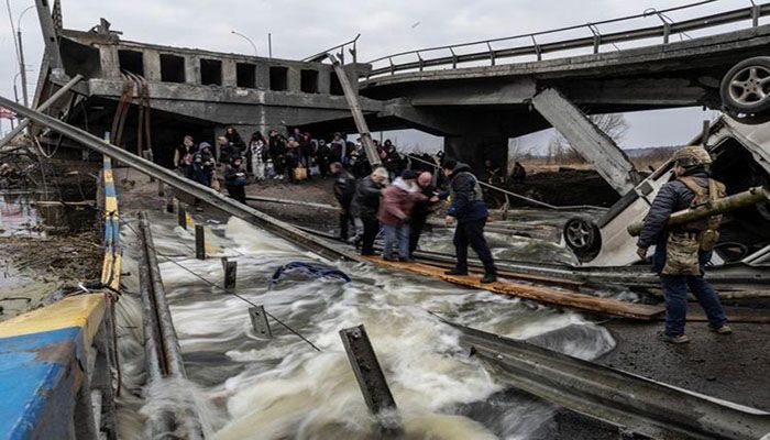 Local residents cross a destroyed bridge as they evacuate from the town of Irpin, after days of heavy shelling on the only escape route used by locals, while Russian troops advance towards the capital, in Irpin, near Kyiv, Ukraine March 7, 2022 || Reuters Photo: Collected  