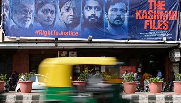 In this file photo taken on March 21, 2022, an autorickshaw moves past a banner of Bollywood movie 'The Kashmir Files' installed outside a cinema hall in the old quarters of Delhi || AFP Photo