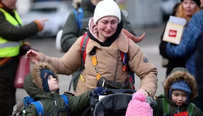 A woman cries next to her children after fleeing from Russia's invasion of Ukraine, at the border crossing in Siret, Romania || Reuters File Photo