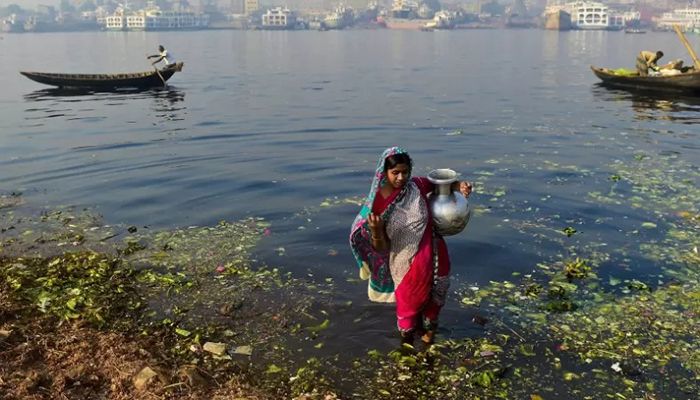 A woman collecting water from the polluted Buriganga River in Dhaka || AFP File Photo