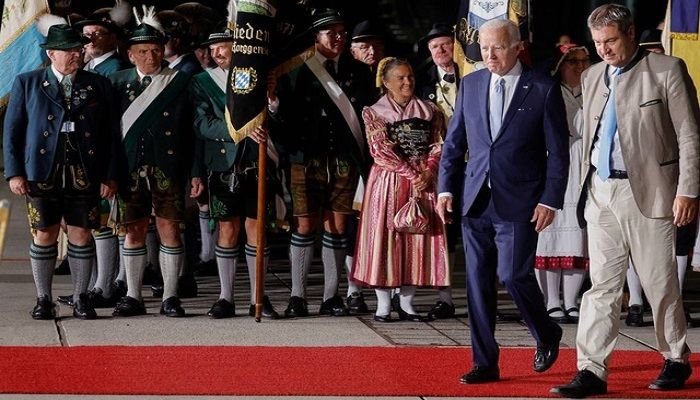 US President Joe Biden walks with Bavaria's State Premier Markus Soeder past people in traditional Bavarian clothes as Biden arrives for a G7 summit aboard Air Force One at Munich International Airport near Munich, Germany June 25, 2022. REUTERS