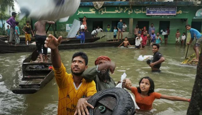 People collect food aid in a flooded residential area following heavy monsoon rainfalls in Companiganj, Sylhet on June 20, 2022 || AFP Photo: Collected  