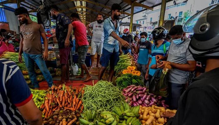 People buy vegetables at a market after authorities relaxed the ongoing curfew for a few hours in Colombo on May 12, 2022 || AFP Photo