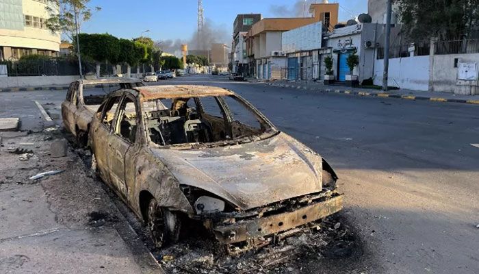 Damaged vehicles are pictured in a street in the Libyan capital Tripoli on August 27, 2022, following clashes between rival Libyan groups. || AFP Photo