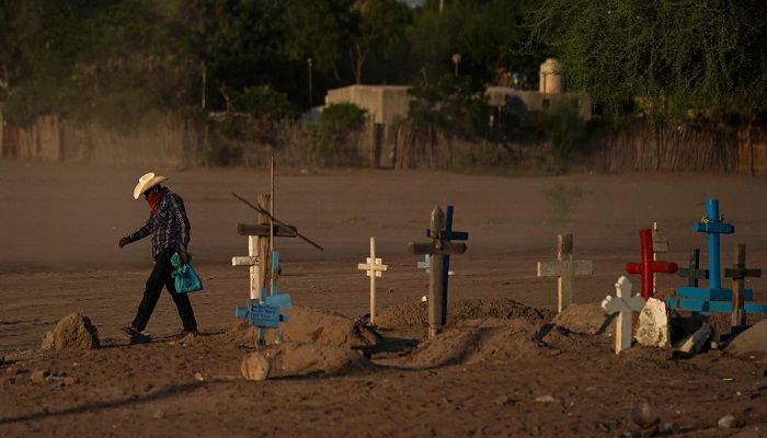 A Yaqui Indigenous wears a bandana over his mouth as he walks through dust past the cemetery where slain water-defense leader Tomás Rojo is buried in Potam, Mexico, Tuesday, Sept. 27, 2022 || Photo: AP