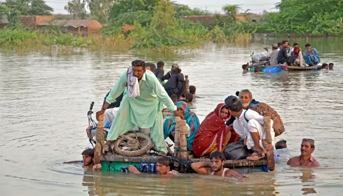 Internally displaced people wade through floodwaters after heavy monsoon rains in Jaffarabad district in Balochistan province on September 8, 2022. || AFP Photo
