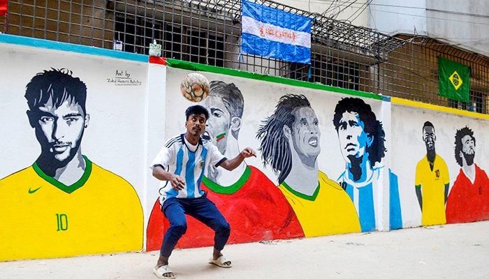 An Argentinian fan is doing various exercises with a football in front of the graffiti of star footballers at KM Dash Lane in Swami Bagh of the capital.