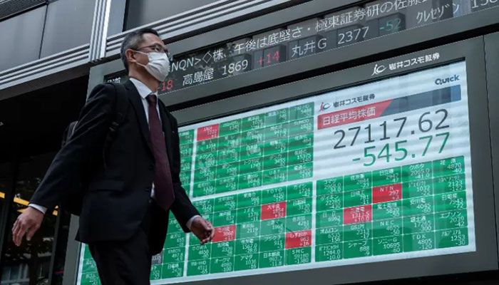 A man walks past an electronic board showing sharply lower numbers on the Tokyo Stock Exchange in Tokyo on November 4, 2022 || AFP Photo